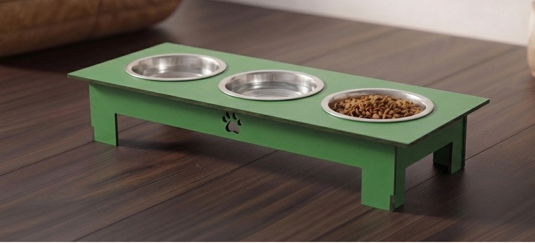 A green elevated pet feeder and water bowl stand with three stainless steel bowls, one filled with dry kibble, shown on a dark wood floor.