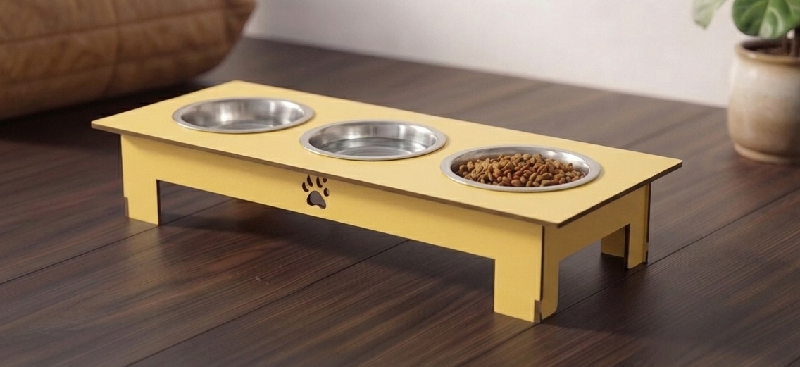 A yellow elevated pet feeder and water bowl stand on a dark wood floor, with two stainless steel bowls and a third bowl filled with kibble. A small paw print cutout is visible on the front.