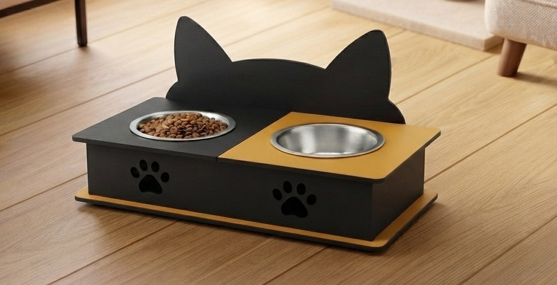 A black and yellow cat feeder and waterer with cat-ear silhouette backrest, shown on a wooden floor with food and water bowls.