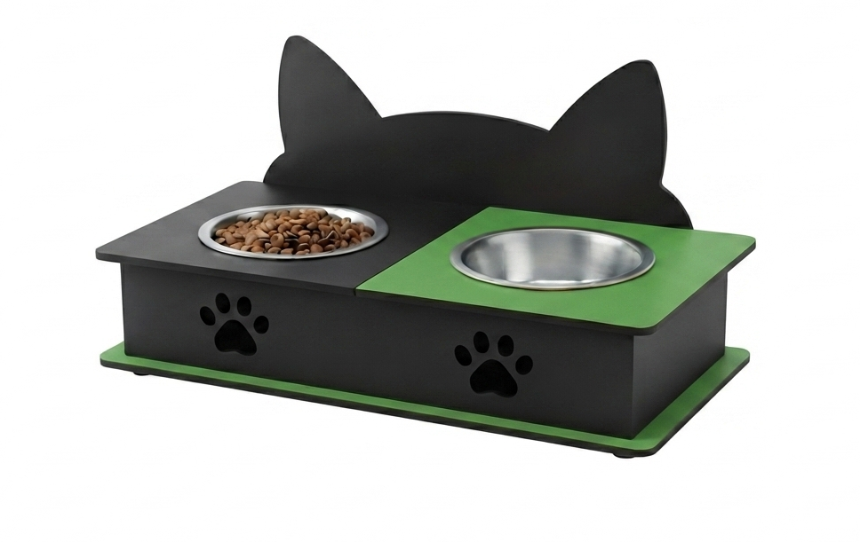 A black and green elevated pet feeder with cat-ear-shaped backrest, two stainless steel bowls, and paw print cutouts on the front, shown on a white background.