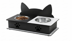 A black cat-shaped dual pet feeder with two bowls, one filled with dry food, shown on a plain white background.