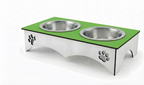A stainless steel elevated pet feeder and water bowl stand with a bright green top surface, two integrated bowls, and paw print cutouts on the sides, shown on a white background.