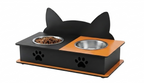 A black and orange elevated pet feeder with cat-ear-shaped backrest, dual bowls, and paw print cutouts, shown on a plain white background.