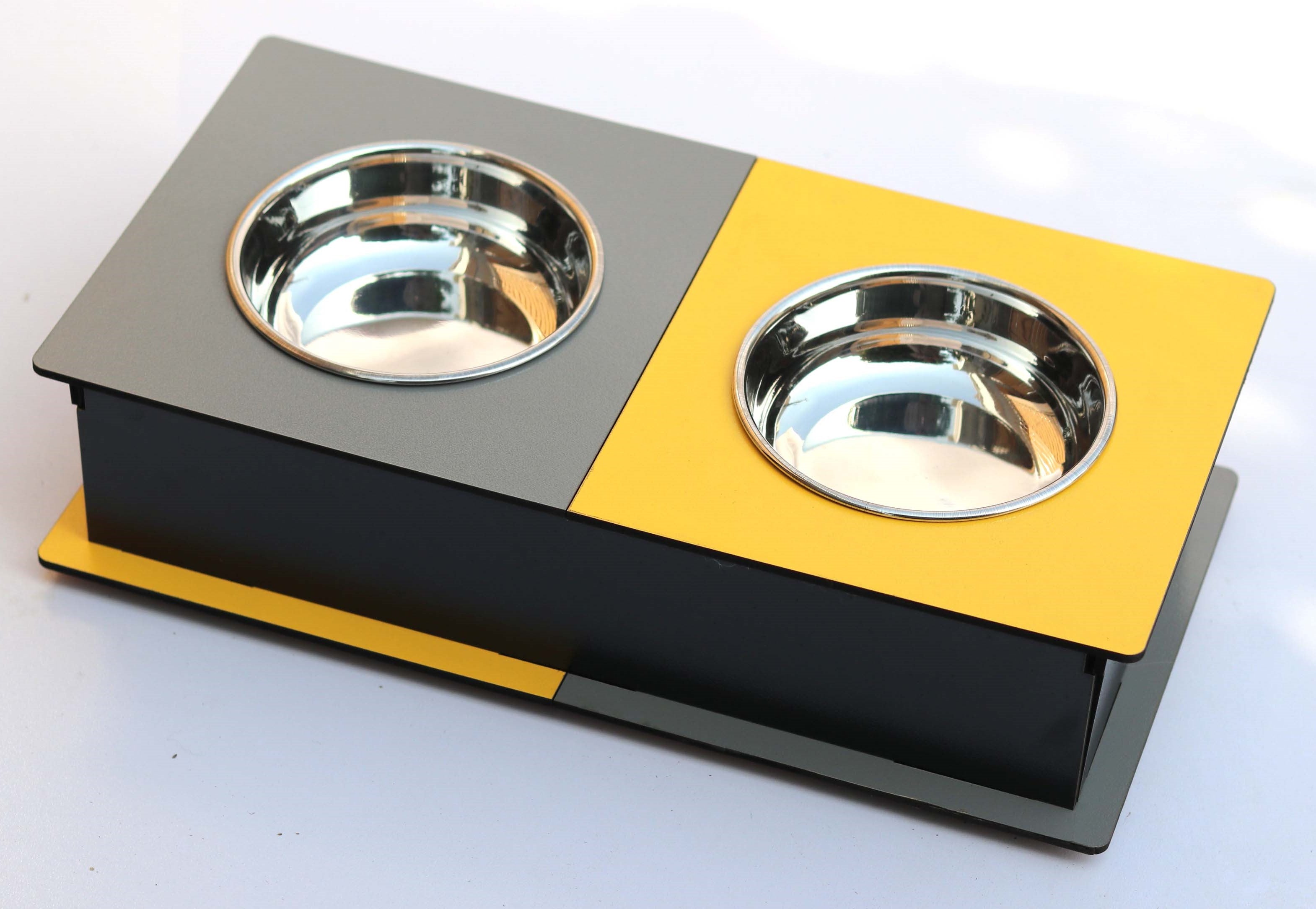 A two-bowl elevated pet feeder and water bowl stand with a gray top, black base, and yellow accents, featuring stainless steel bowls.