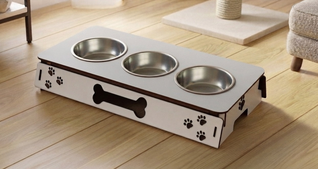 A white elevated pet feeder and water bowl stand with three stainless steel bowls, decorated with black paw prints and a bone graphic, shown on a light wood floor.