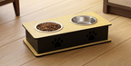A two-bowl elevated pet feeder and waterer stand with a light wood top, black side panels featuring paw print cutouts, and a matching base, shown on a wooden floor with one bowl filled with dog food.