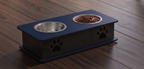 A raised pet feeder and water bowl stand with two bowls, one filled with kibble, placed on a dark wood floor. The stand is dark blue and black with black paw print details.