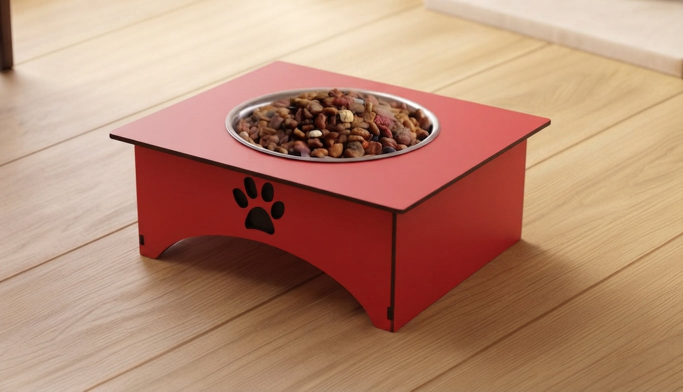 A red elevated pet food bowl with a stainless steel insert filled with dry dog food, placed on a light wood floor. The bowl features a black paw print cutout on the front side.