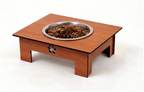 A wooden elevated pet feeder table with a stainless steel bowl filled with dry pet food, set against a plain white background.