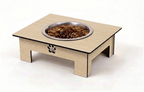 A wooden elevated pet feeder table with a stainless steel bowl filled with dry dog food, shown on a plain white background. The table has a light natural wood grain finish, black edging, a paw print cutout on the front, and open side supports.
