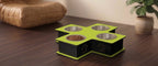A four-bowl elevated pet feeder and waterer with a bright lime green top and black base, styled on a dark wood table in a home setting.