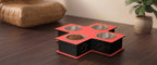 A 4-bowl pet feeder and water fountain elevated feeder with a red and black cross-shaped base, featuring stainless steel bowls and a bowl filled with dry food, set on a dark wooden table in a home environment.