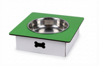 A square elevated pet feeder and water bowl stand with a green top platform, a stainless steel bowl, and a white base with a black bone-shaped cutout, shown on a white background.