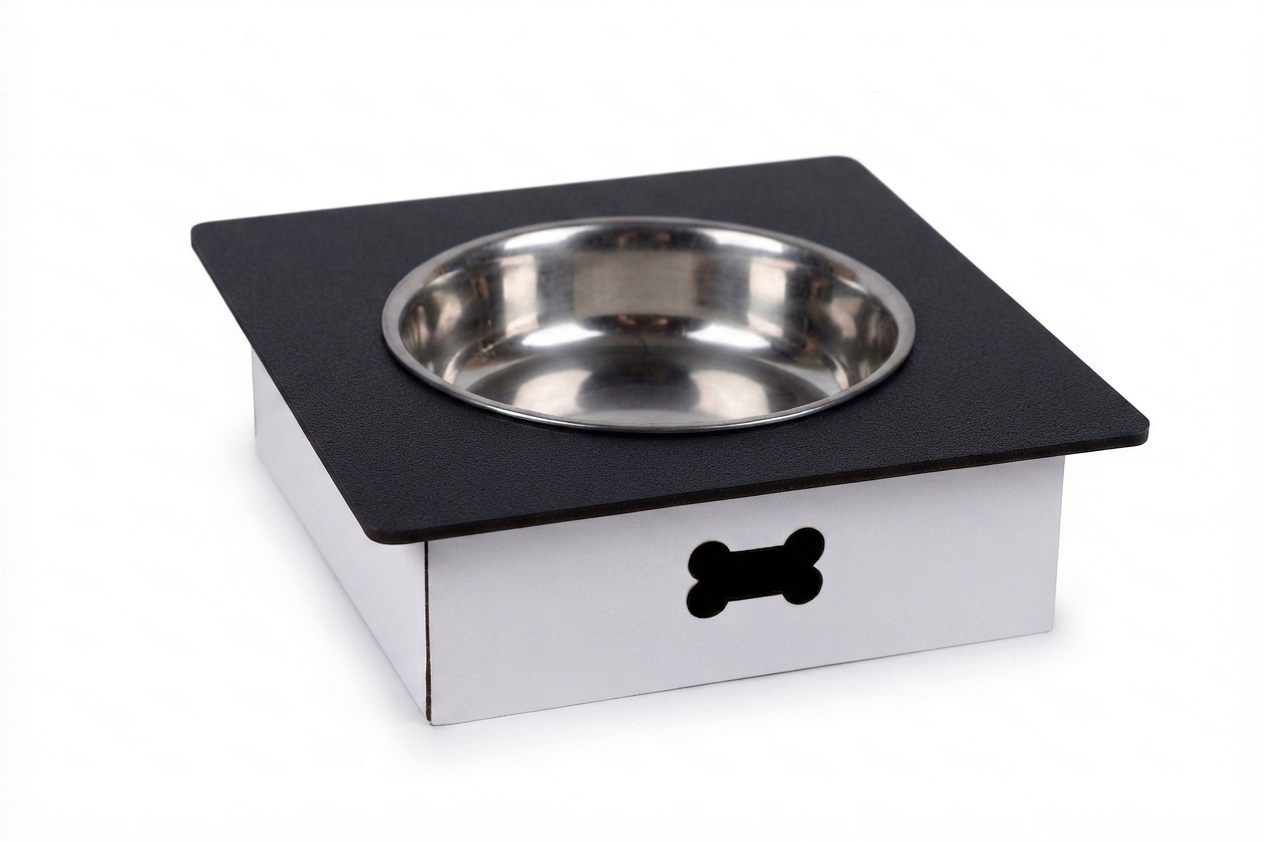 A square pet feeder or elevated bowl stand with a black top surface, a stainless steel bowl, and a white base with a black bone-shaped cutout, shown on a white background.