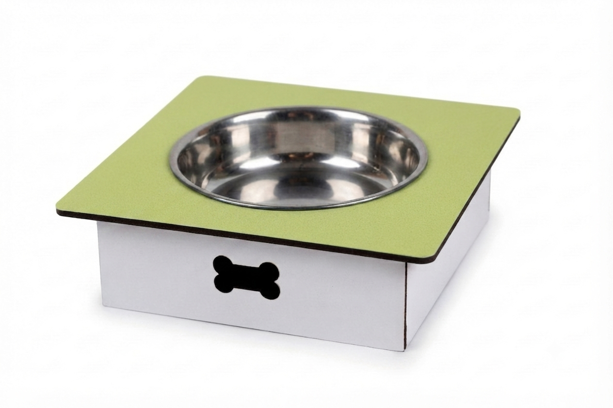 A square elevated pet feeder and water bowl stand with a light green top surface, a stainless steel bowl, and a white base with a black bone-shaped cutout, shown on a white background.