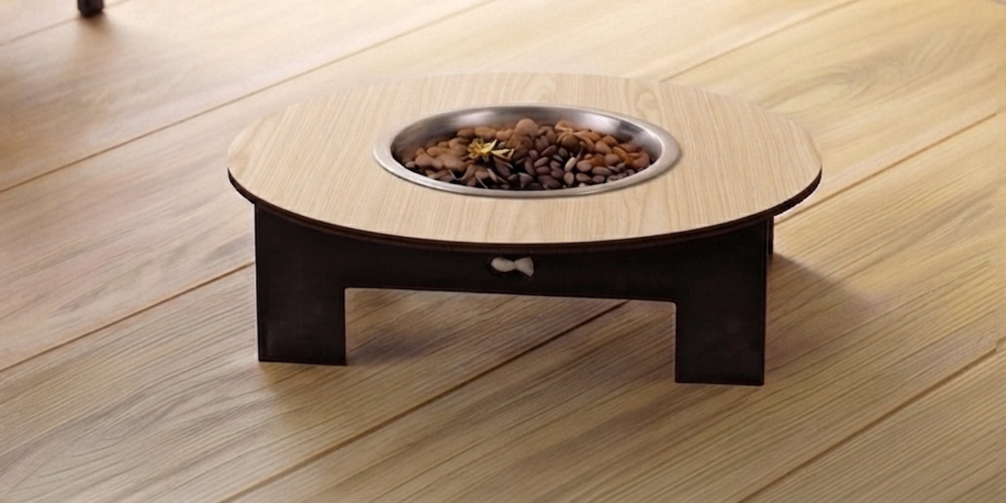 A low round wooden pet feeder table with a dark base and a metal bowl filled with kibble, placed on a light wood floor.