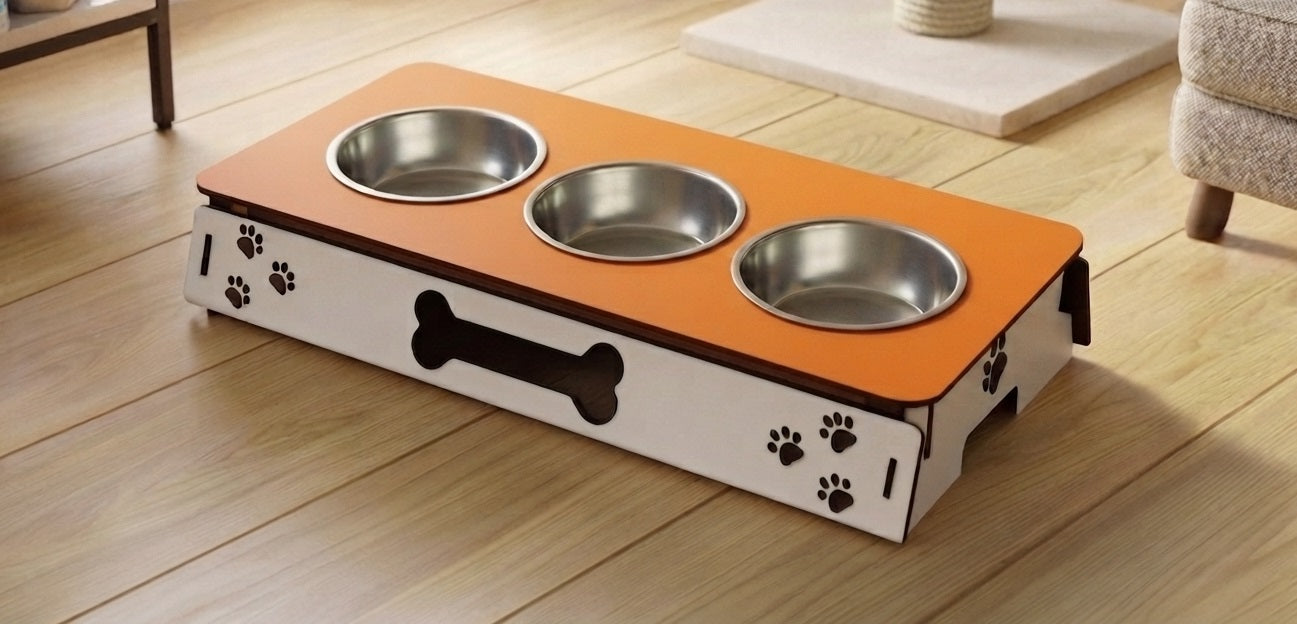 A three-bowl elevated pet feeder and waterer with an orange top, white sides, and black paw print and bone graphics, shown on a light wood floor in a room setting.