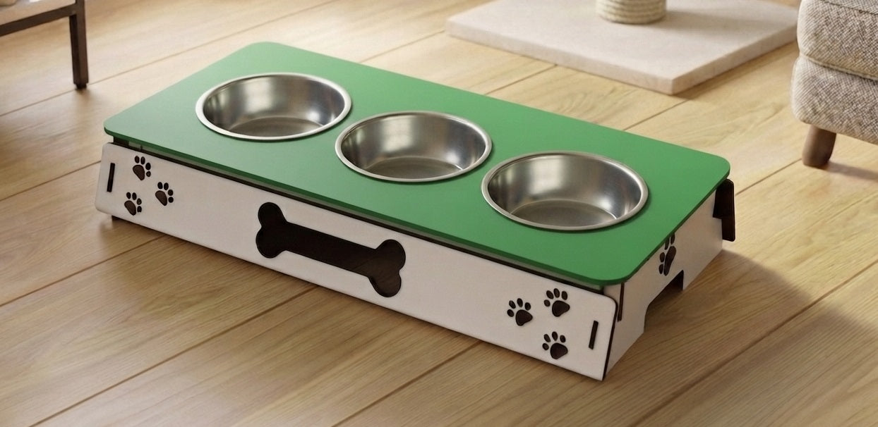 A three-bowl elevated pet feeder and water fountain with a green top surface, stainless steel bowls, and a white base decorated with black paw prints and a bone cutout, shown on a wooden floor.