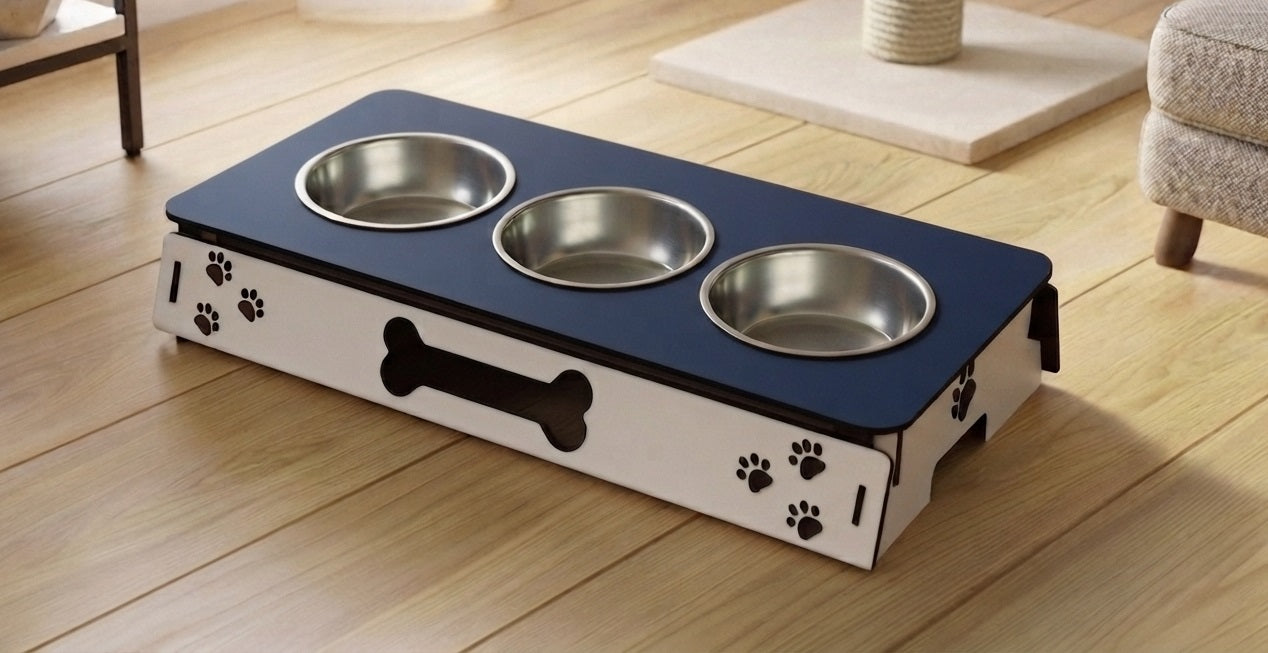 A pet elevated feeding station with three stainless steel bowls, featuring a navy blue top and a white side panel decorated with black paw prints and a bone silhouette, shown on a wooden floor.