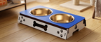 A pet elevated feeding station with two stainless steel bowls, set on a wooden floor in a home environment.